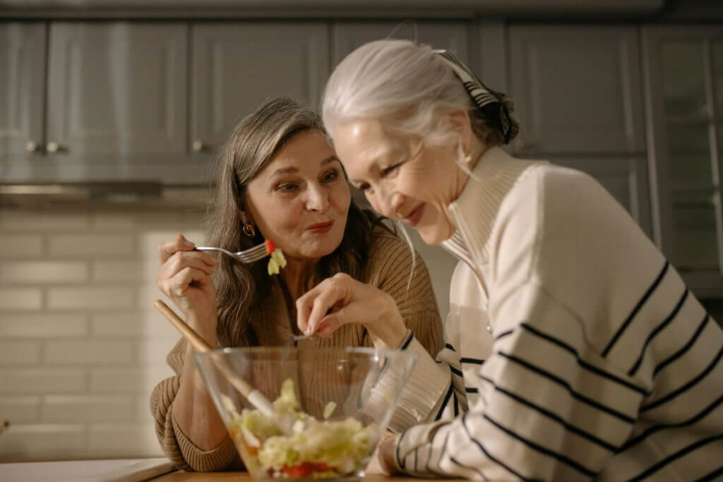 senior with dementia with caregiver eating a salad