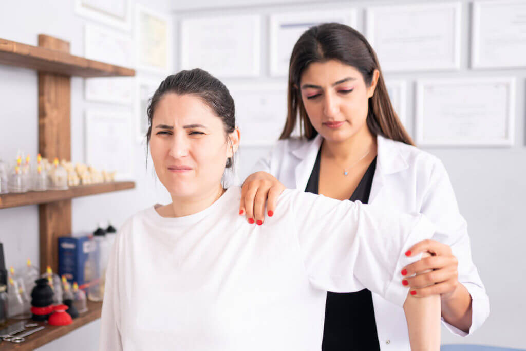 A doctor is examining her patient's shoulder for rotator cuff tear injury.